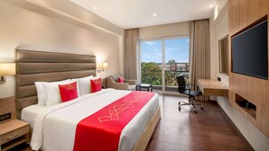 A hotel room with a large bed, a desk, a chair, and a TV.