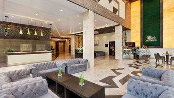 A spacious lobby with a reception desk, seating area, and a coffee bar.
