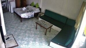 Ein Zimmer mit einem Bett, einem grünen Sofa, einem kleinen Tisch und einem Schrank.