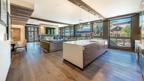 A spacious kitchen with a large island, modern cabinetry, and large windows offering views of the outdoors. - Lumin 3 - Blu Bathworks tubs and Waterworks fixtures. (Snowmass)