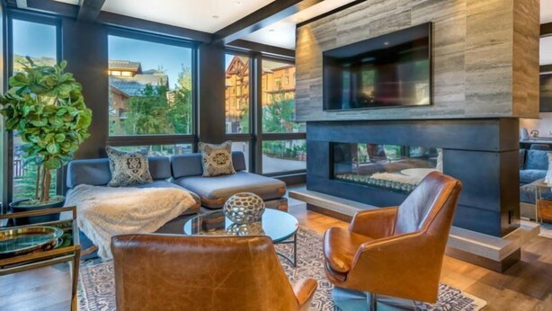 A modern living room with a fireplace, large windows, and a television mounted on the wall. - Lumin 3 - Blu Bathworks tubs and Waterworks fixtures. (Snowmass)
