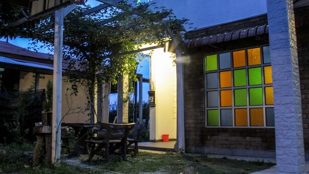 A building with a traditional architectural style, featuring a pergola and a patio area with outdoor furniture. - Multaqa Suite & Residence (Marang)