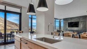 A modern kitchen with a large island, a built-in sink, and pendant lighting. - One Snowmass West 303 (SNOWMASS VILLAGE)