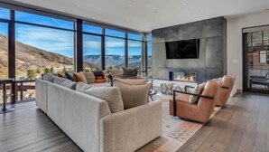 A modern living room with a large window, a fireplace, and a sofa. - One Snowmass West 303 (SNOWMASS VILLAGE)