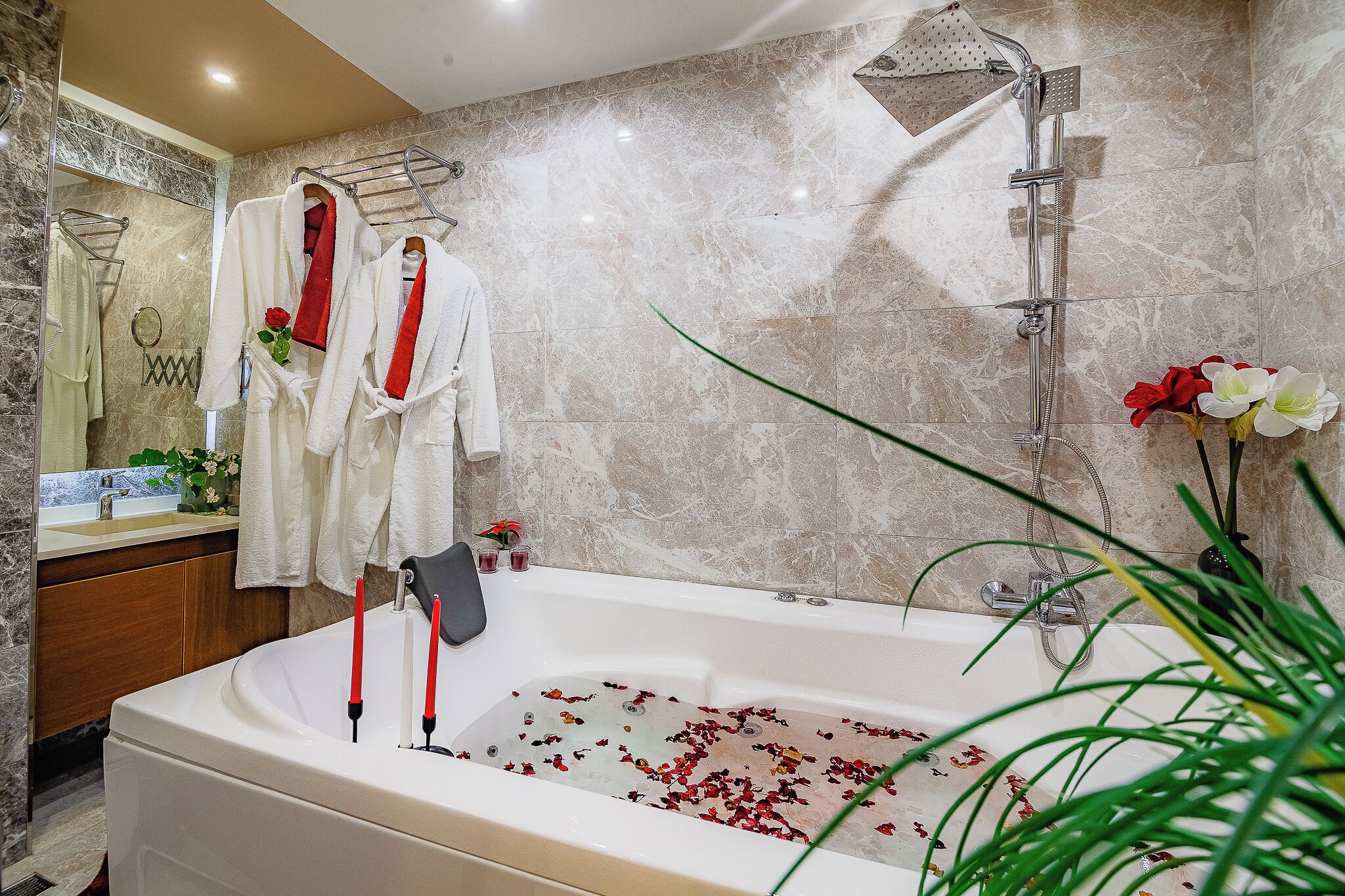 A bathroom with a bathtub filled with rose petals, a shower, and a mirror with a towel rack.