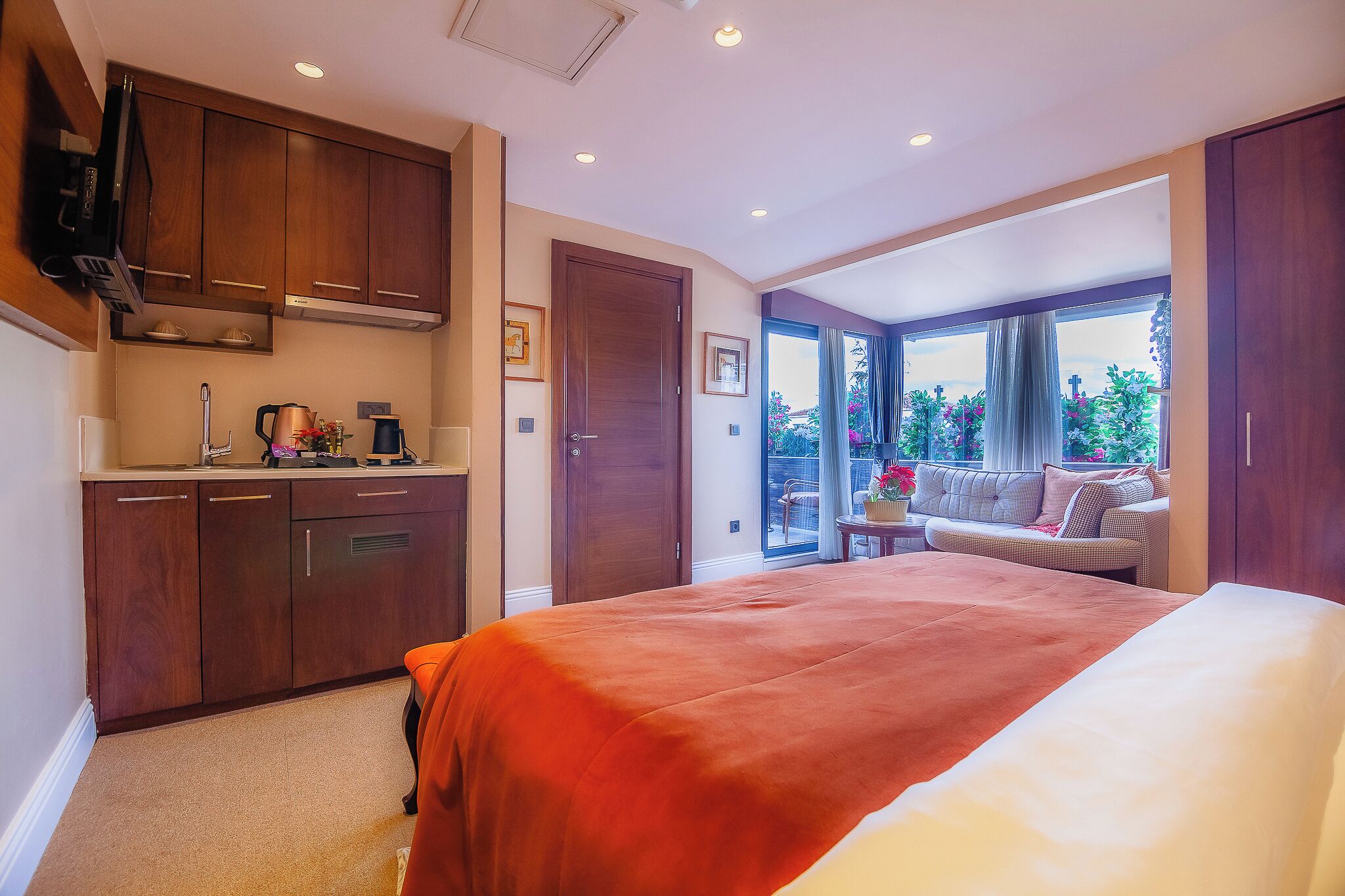 A bedroom with a large bed, a kitchenette, and a view of the outdoors.