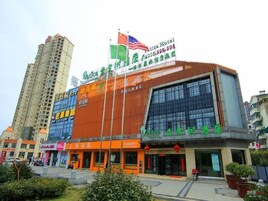 A hotel with a prominent sign featuring multiple flags and a contact number.