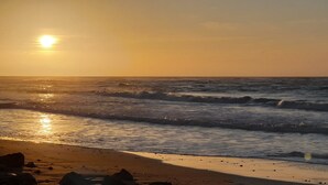 Ein Strand mit Wellen und einem untergehenden Sonnenuntergang.