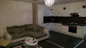 A compact living space with a sofa, a small round table, a kitchenette, and a dining area. - Cozy luxury 4 bedroom. In the heart of Heidelberg (Kirchheim)