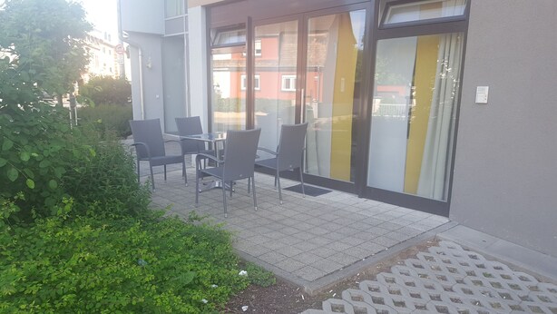 A patio area with outdoor seating and a glass door leading to a building. - Cozy luxury 4 bedroom. In the heart of Heidelberg (Kirchheim)
