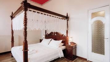 A four-poster bed with a white canopy, a wooden nightstand with a lamp, and a white door with a frosted glass panel.
