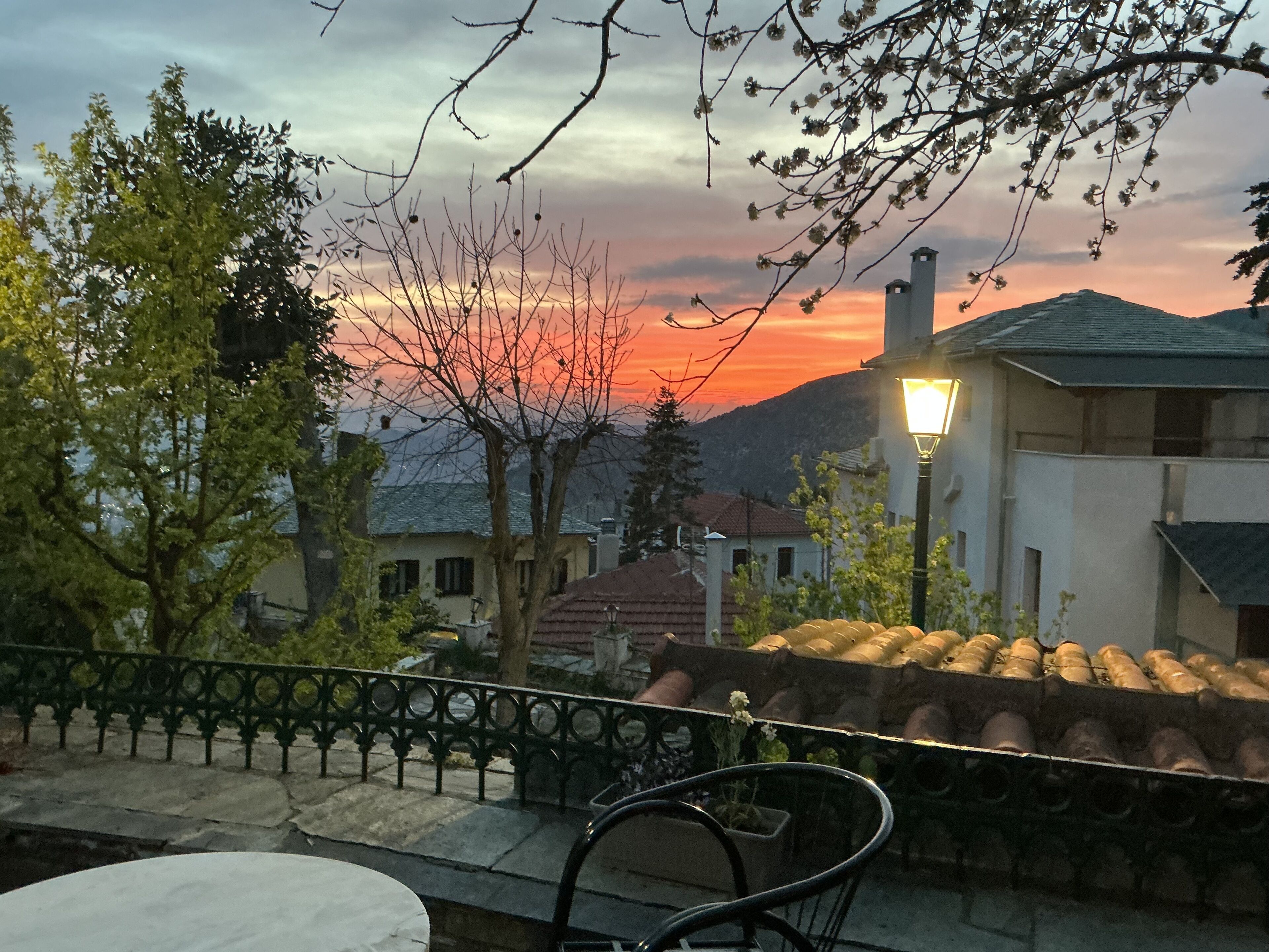 Une terrasse offrant une vue sur le coucher de soleil, avec une rambarde en métal et une table.