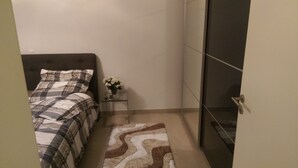 Ein Schlafzimmer mit einem Bett, einem Nachttisch, einem kleinen Tisch mit Blumen und einer Schiebetür.