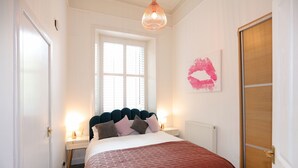 Een slaapkamer met een bed, nachtkastjes, een raam en een deur.