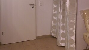 Une pièce avec une porte blanche, un interrupteur et un rideau orné d’un motif circulaire.