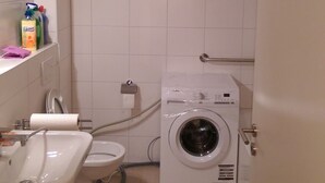 Une petite salle de bain comprenant un lavabo, des toilettes et un lave-linge à chargement frontal.