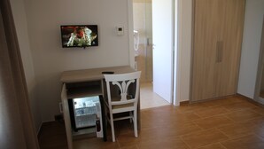 A room with a wooden desk, a chair, a television mounted on the wall, and a wardrobe. - Nebrodi Rooms Monte San Giovanni (San Marco d'Alunzio)
