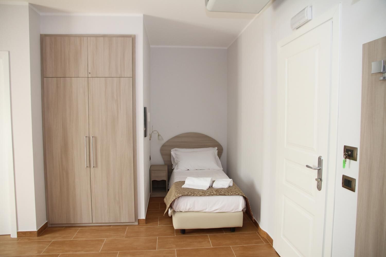 A bedroom with a bed, a wardrobe, and a door.