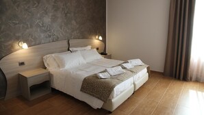 A modern hotel room with a large bed, bedside tables, and a headboard with built-in lighting. - Nebrodi Rooms Monte San Giovanni (San Marco d'Alunzio)