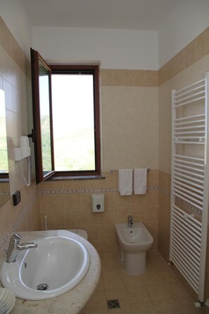 A bathroom with a bathtub, a sink, a bidet, and a towel rack. - Nebrodi Rooms Monte San Giovanni (San Marco d'Alunzio)