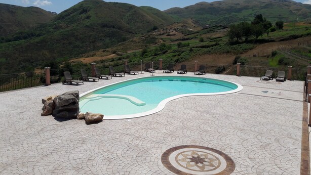 A pool area with lounge chairs and a decorative tile pattern. - Nebrodi Rooms Monte San Giovanni (San Marco d'Alunzio)
