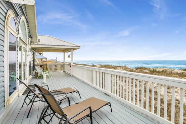 Una terraza de madera con mobiliario exterior y vistas a la playa.