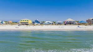 Una propiedad frente a la playa con varias casas, algunas elevadas sobre pilotes, y una playa arenosa al fondo.