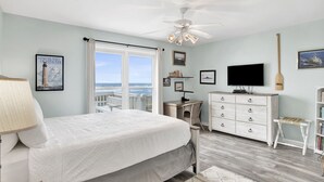 Un dormitorio con cama, escritorio, televisor y vista al océano.