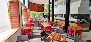 Enjoy meals in a spacious dining area with wooden tables and comfortable seating, surrounded by lush greenery views.