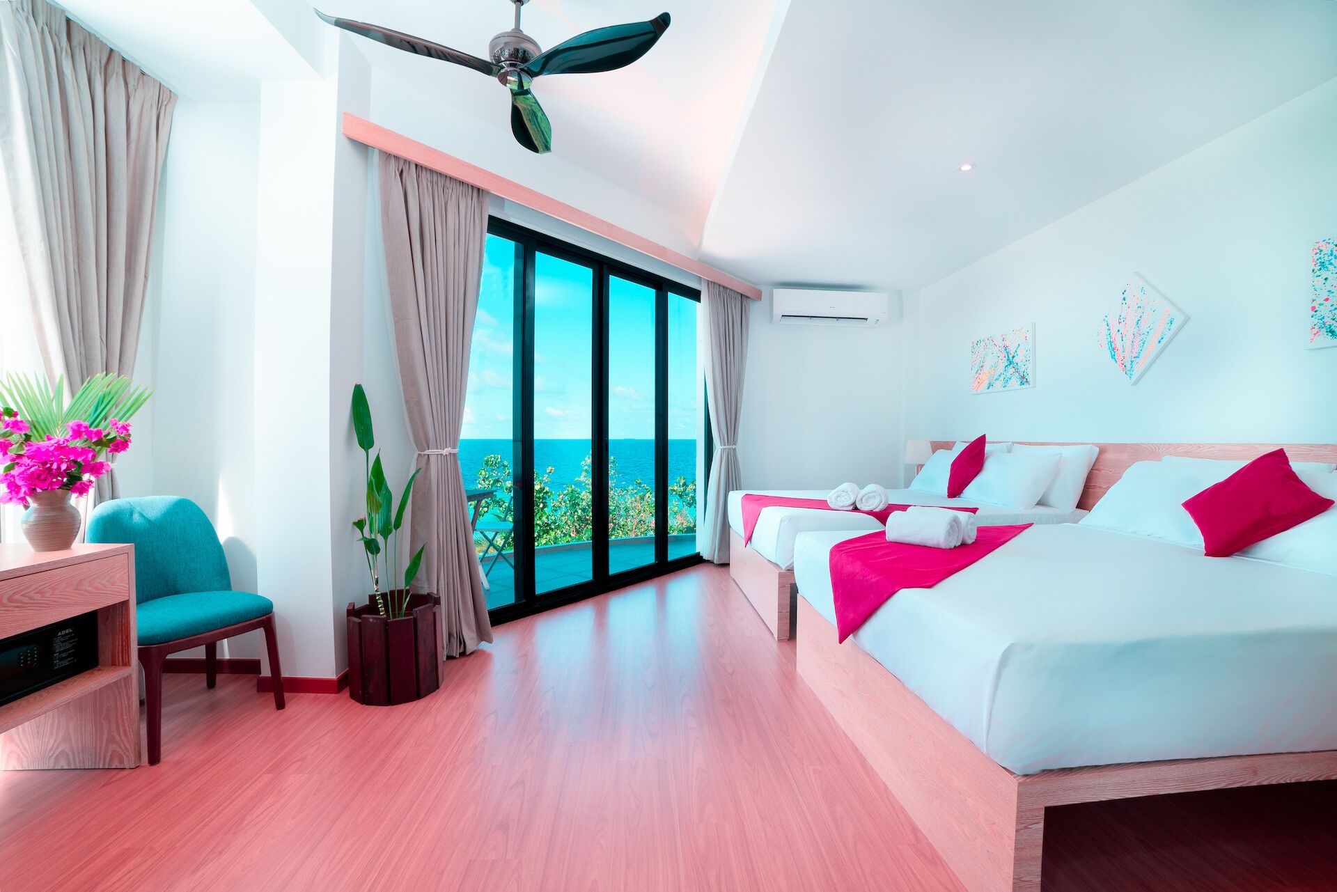 Una habitación de hotel moderna con un balcón grande, un ventilador de techo y una cama con ropa de cama blanca y rosa.
