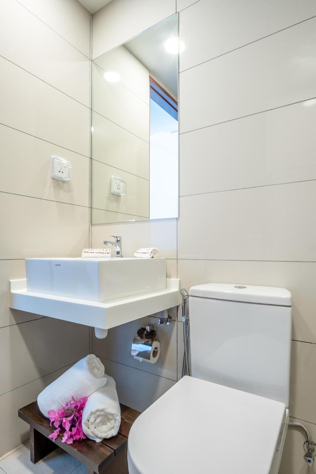 A modern bathroom with a white sink, mirror, and toilet.