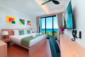 A hotel room with a bed, a desk, a chair, a TV, and a balcony with a view.