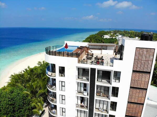 A hotel with multiple balconies overlooking a beach and ocean.