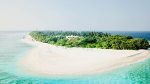An aerial view of a tropical island with a white sandy beach, clear turquoise waters, and dense green vegetation. - Ranthari Hotel and Spa Ukulhas Maldives (Ukulhas)
