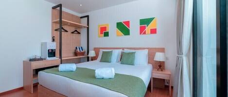 A hotel room with a bed, a desk, a chair, a wardrobe, and a window.