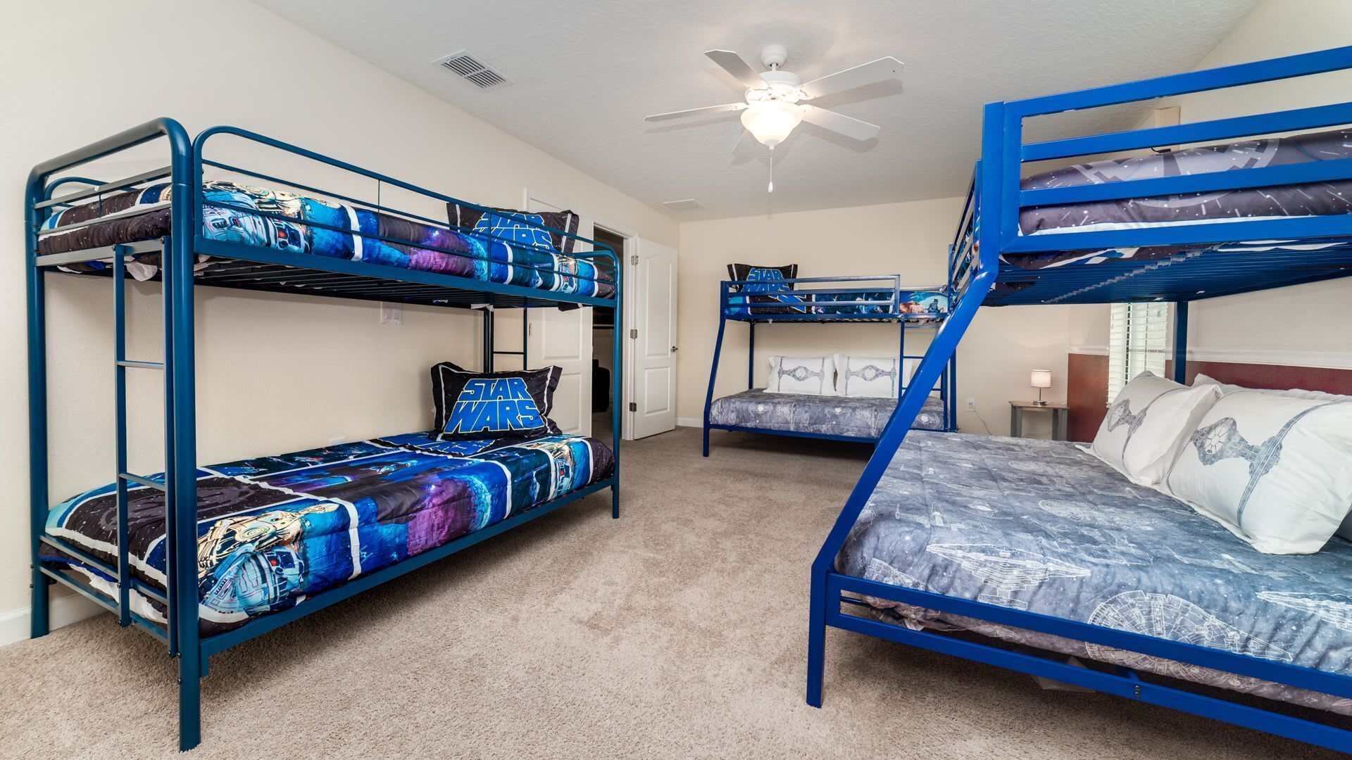 A room with bunk beds, a ceiling fan, and a door.