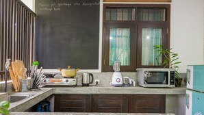 A kitchen with a toaster, blender, kettle, and microwave on the counter. There is a chalkboard with a message about garbage disposal. - Dollyz Home (Madampagama)