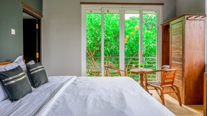 A bedroom with a bed, two pillows, a wooden chair, a small table, and a wardrobe. - Dollyz Home (Madampagama)