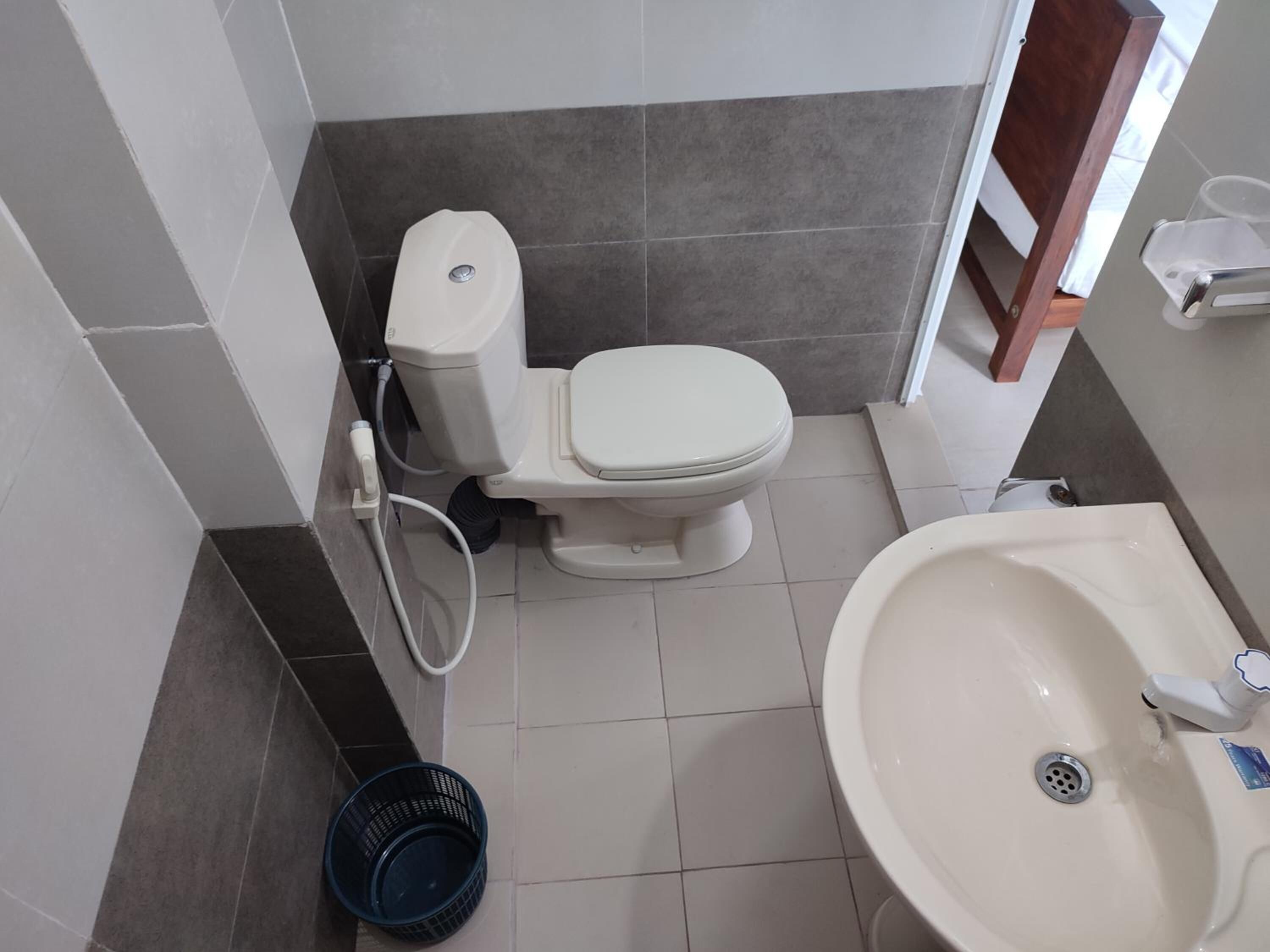 Un baño con inodoro, lavamanos y una cesta azul en el suelo.
