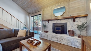 A living room with a stone fireplace, a wooden ceiling, a large mirror, a sofa, and a coffee table. - Snowflower 3 Remodeled and Modern, Private Washer Dryer with Fireplace by RedAwning (Mammoth Lakes)