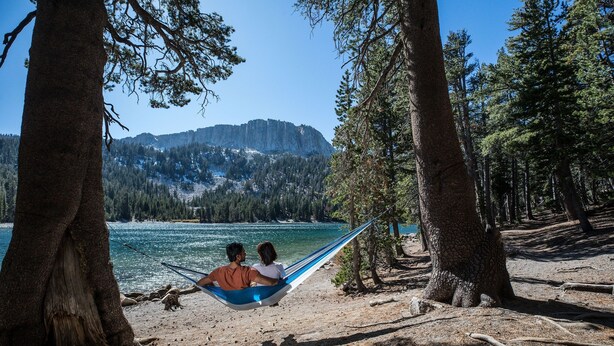 A hammock between two trees overlooking a lake with mountains in the background. - Sunstone 209 Ski-In Ski-Out, Gorgeous Mountain Views, Heated Pool Jacuzzi by RedAwning (Mammoth Lakes)
