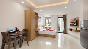 A modern hotel room with a dining area, a bed with a view, and a kitchen area. - XO Hotel & Apartments (Nha Trang)
