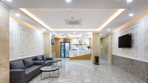 A hotel lobby with a reception desk, a sofa, and a TV. - XO Hotel & Apartments (Nha Trang)