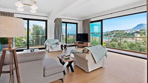 Amplia sala de estar con televisor grande, asientos cómodos y un balcón con vistas panorámicas.