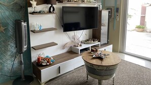 Een moderne woonkamer met een flatscreen televisie, houten planken en een ronde salontafel.