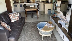 Een moderne woonkamer met een leren bank, een eettafel en een keuken op de achtergrond.