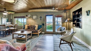 A spacious living area with a wooden ceiling, a dining table, and a comfortable seating arrangement. - Private Beach Access- Direct Oceanfront (Melbourne Beach)