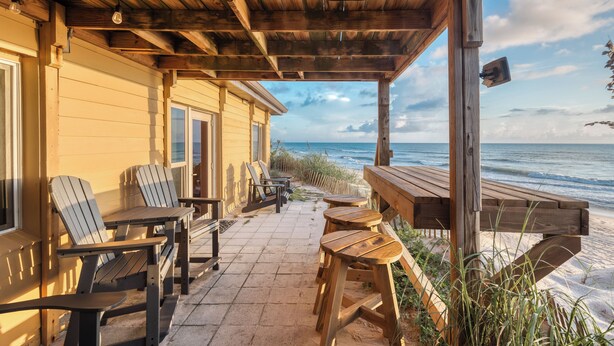 A wooden deck with Adirondack chairs and a wooden table, overlooking the ocean. - Private Beach Access- Direct Oceanfront (Melbourne Beach)