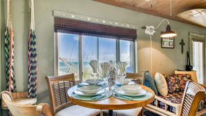 A dining area with a round wooden table set for four, surrounded by wicker chairs. - Private Beach Access- Direct Oceanfront (Melbourne Beach)