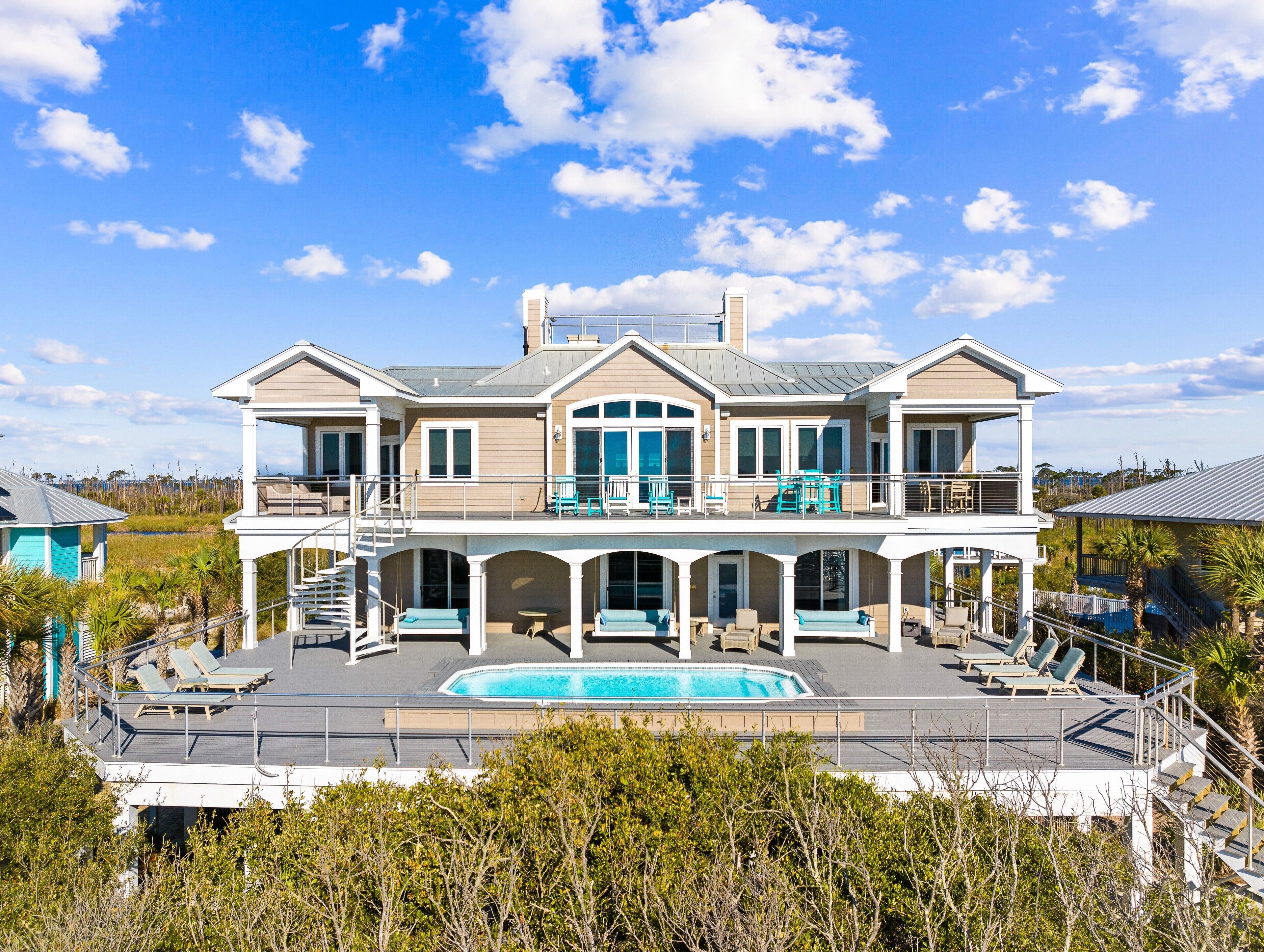A large two-story house with a swimming pool, multiple balconies, and a covered patio area.
